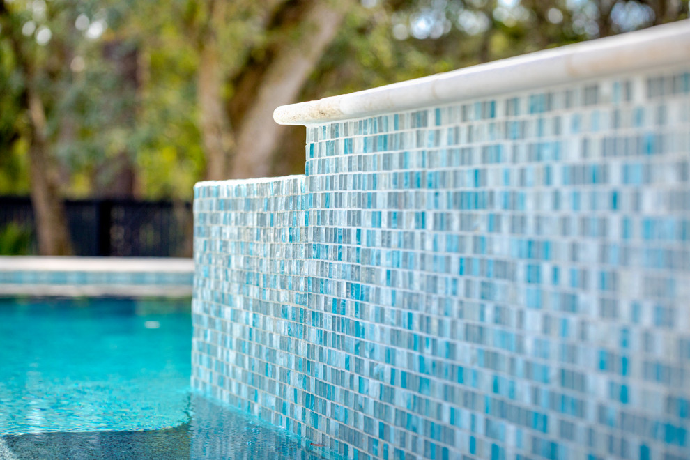 Diseño de piscina actual de tamaño medio rectangular en patio trasero con adoquines de hormigón
