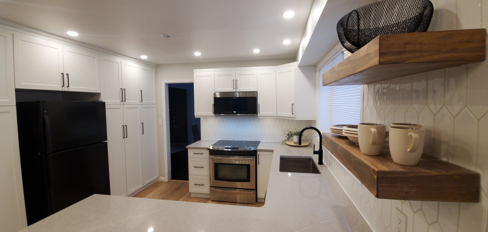 Inspiration for an u-shaped vinyl floor and multicolored floor eat-in kitchen remodel with an undermount sink, shaker cabinets, white cabinets, quartz countertops, white backsplash, ceramic backsplash, black appliances, a peninsula and gray countertops