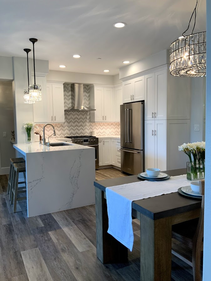 Inspiration for a small modern u-shaped eat-in kitchen in Los Angeles with a single-bowl sink, recessed-panel cabinets, white cabinets, quartz benchtops, mosaic tile splashback, stainless steel appliances, vinyl floors, a peninsula and white benchtop.