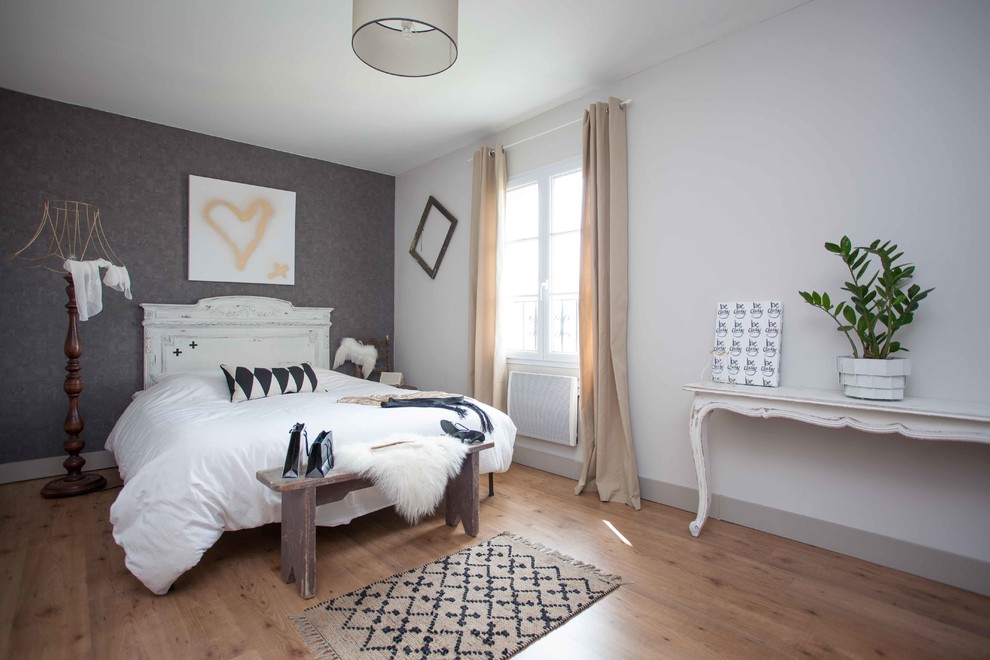 Country bedroom in Other with grey walls and light hardwood floors.