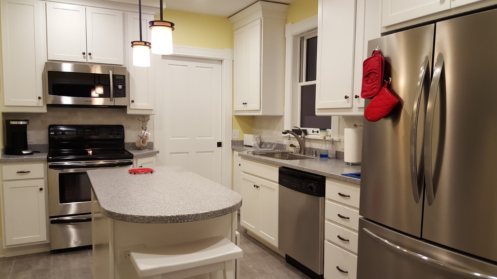 Example of a mid-sized transitional l-shaped vinyl floor enclosed kitchen design with an undermount sink, shaker cabinets, white cabinets, solid surface countertops, multicolored backsplash, stone tile backsplash, stainless steel appliances and an island