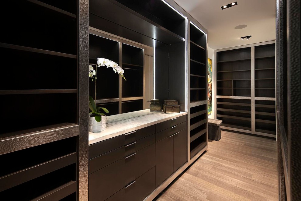 Expansive contemporary men's walk-in wardrobe in Los Angeles with brown cabinets, medium hardwood floors and flat-panel cabinets.