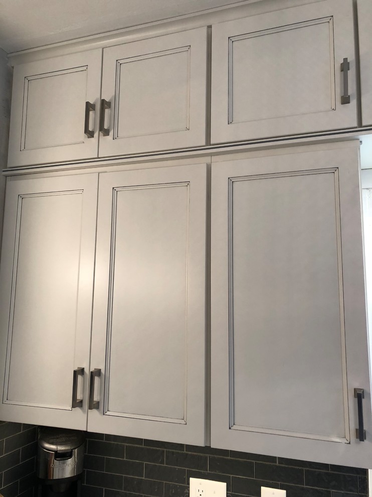 Small transitional l-shaped laminate floor and gray floor eat-in kitchen photo with an undermount sink, flat-panel cabinets, white cabinets, quartz countertops, gray backsplash, subway tile backsplash, white appliances and white countertops