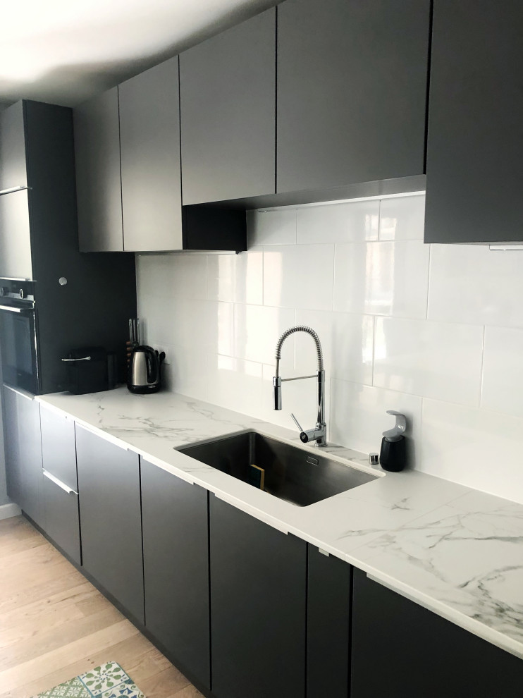 Large contemporary l-shaped kitchen/diner in Toulouse with an integrated sink, beaded cabinets, stainless steel cabinets, quartz worktops, white splashback, glass tiled splashback, coloured appliances, light hardwood flooring, an island, brown floors and white worktops.