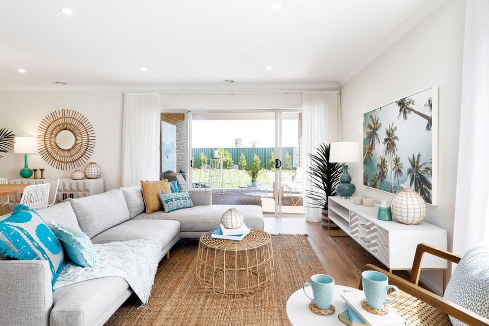 Beach style living room in Melbourne with white walls, medium hardwood floors and brown floor.