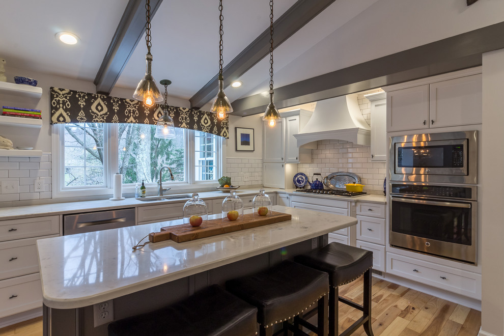 Enclosed kitchen - large transitional u-shaped medium tone wood floor and brown floor enclosed kitchen idea with an undermount sink, shaker cabinets, white cabinets, quartzite countertops, white backsplash, subway tile backsplash, stainless steel appliances and an island