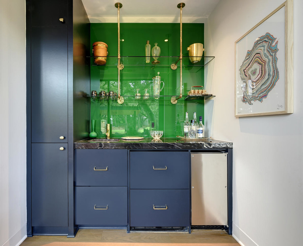 Mid-sized transitional single-wall wet bar in Austin with an integrated sink, flat-panel cabinets, blue cabinets, green splashback, glass sheet splashback, light hardwood floors, beige floor and marble benchtops.