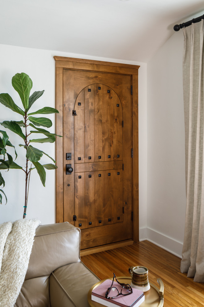 Photo of a medium sized mediterranean front door in San Diego with white walls, medium hardwood flooring, a single front door, a medium wood front door, brown floors and a vaulted ceiling.