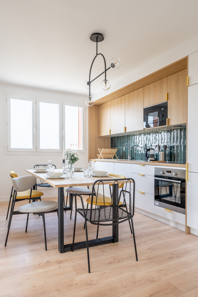 Inspiration for a mid-sized scandinavian single-wall eat-in kitchen in Paris with an undermount sink, flat-panel cabinets, light wood cabinets, wood benchtops, green splashback, ceramic splashback, stainless steel appliances, light hardwood floors and no island.