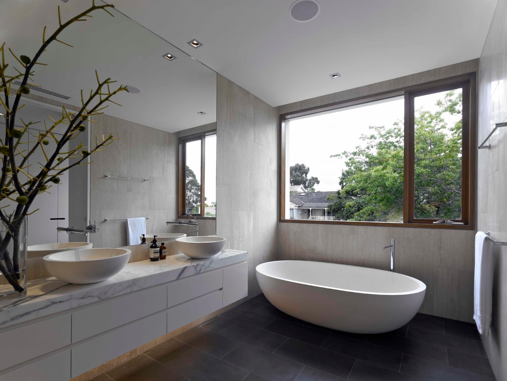 This is an example of a contemporary bathroom in Melbourne with a freestanding tub, a vessel sink and gray tile.