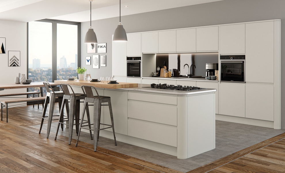 Inspiration for a large contemporary l-shaped open plan kitchen in Sussex with flat-panel cabinets, solid surface benchtops, panelled appliances, with island, white cabinets, metallic splashback and mirror splashback.