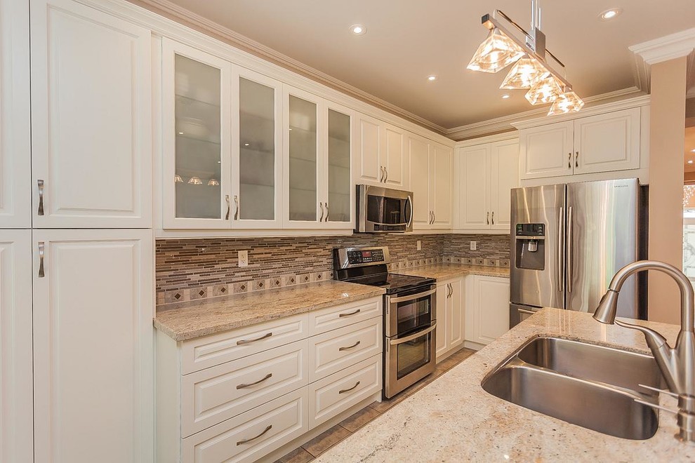 Inspiration for a large transitional l-shaped ceramic tile eat-in kitchen remodel in Toronto with a double-bowl sink, raised-panel cabinets, white cabinets, granite countertops, multicolored backsplash, matchstick tile backsplash, stainless steel appliances and an island
