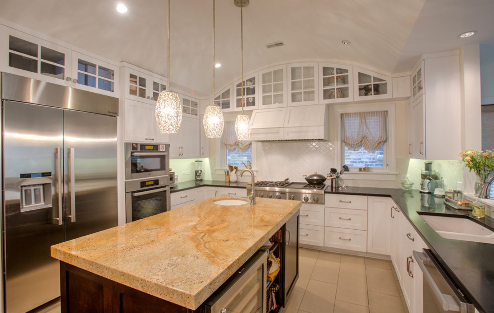 Large traditional u-shaped kitchen in Chicago with a double-bowl sink, shaker cabinets, white cabinets, soapstone benchtops, white splashback, subway tile splashback, stainless steel appliances, porcelain floors, with island, beige floor and black benchtop.