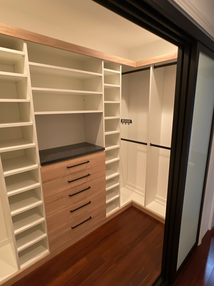This is an example of a mid-sized modern walk-in wardrobe in Los Angeles with flat-panel cabinets and medium hardwood floors.