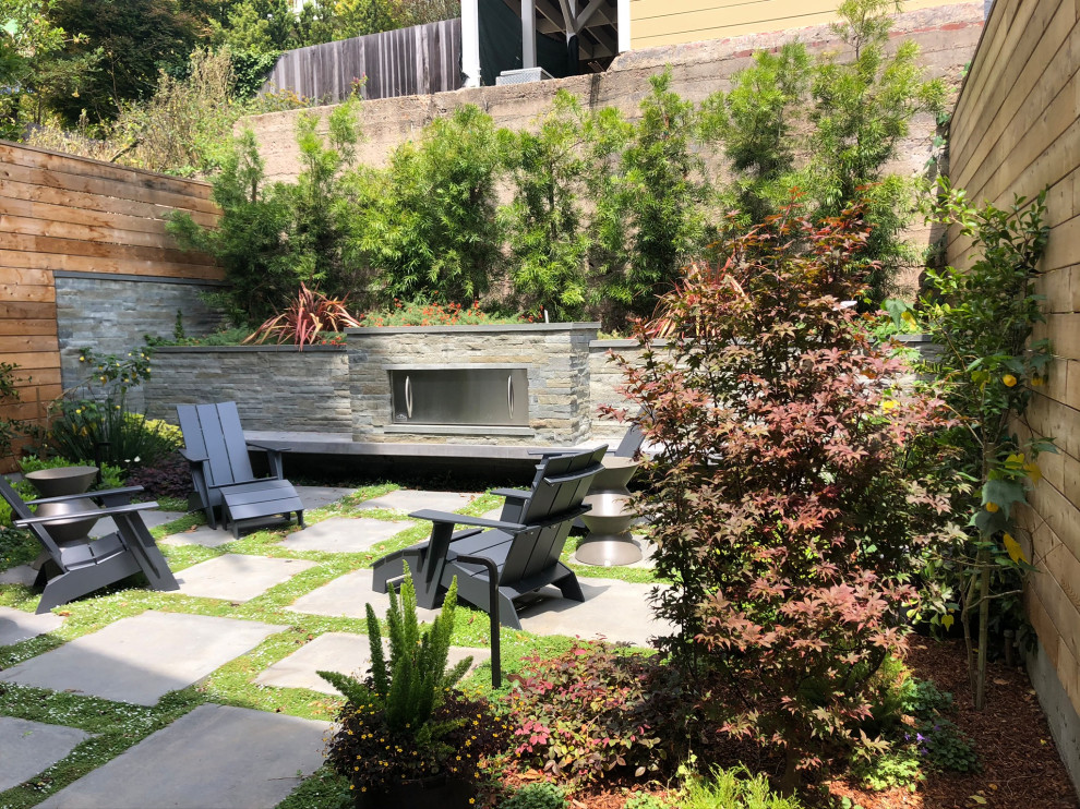 Inspiration for a small transitional backyard partial sun garden in San Francisco with with fireplace, river rock and a wood fence.