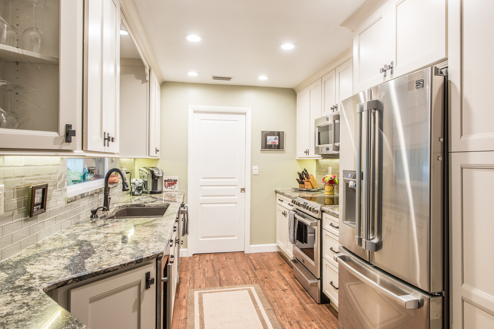 Eat-in kitchen - mid-sized transitional galley porcelain tile and brown floor eat-in kitchen idea with an undermount sink, white cabinets, quartz countertops, gray backsplash, glass tile backsplash, stainless steel appliances, no island and shaker cabinets