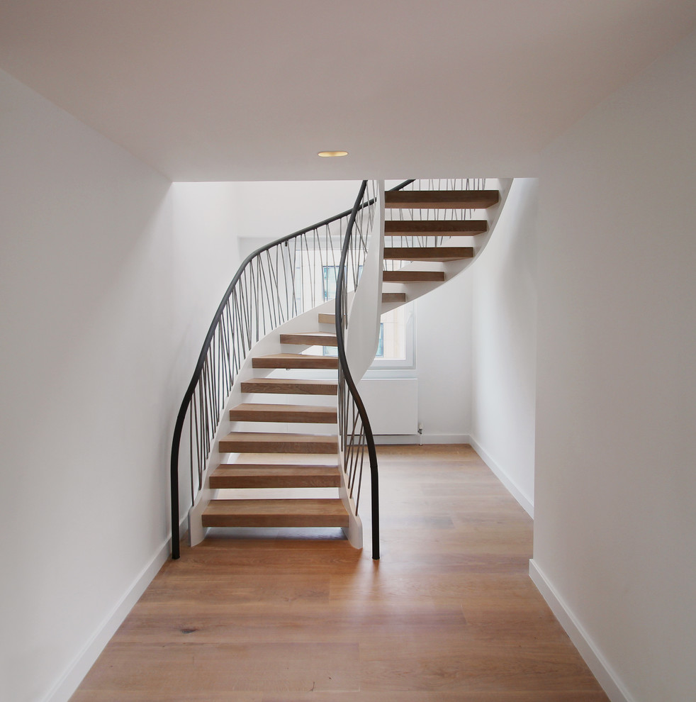 Photo of a mid-sized contemporary wood curved staircase in London with open risers.
