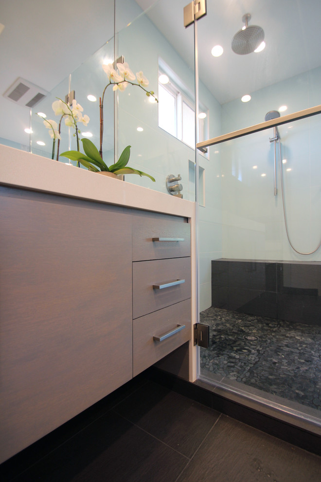 Photo of a contemporary bathroom in San Francisco with a drop-in sink, flat-panel cabinets, grey cabinets, engineered quartz benchtops, a freestanding tub, a corner shower, a two-piece toilet, gray tile, porcelain tile, white walls and porcelain floors.