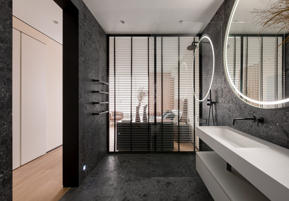 This is an example of a mid-sized contemporary master wet room bathroom in Other with flat-panel cabinets, white cabinets, a freestanding tub, a wall-mount toilet, black tile, porcelain tile, black walls, ceramic floors, an integrated sink, solid surface benchtops, black floor, an open shower, white benchtops, an enclosed toilet, a single vanity and a floating vanity.