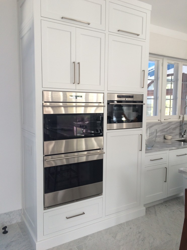 Photo of a large transitional l-shaped kitchen in Miami with an undermount sink, shaker cabinets, white cabinets, grey splashback, stainless steel appliances, with island, quartzite benchtops, stone slab splashback, marble floors and grey floor.