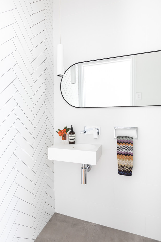 Design ideas for a mid-sized contemporary powder room in Brisbane with a one-piece toilet, white tile, ceramic tile, white walls, cement tiles, a wall-mount sink, engineered quartz benchtops, grey floor and white benchtops.