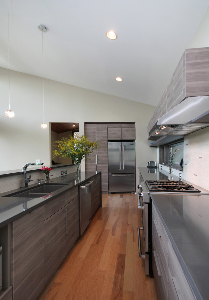 Inspiration for a contemporary u-shaped kitchen remodel with an undermount sink, flat-panel cabinets, medium tone wood cabinets, beige backsplash and stainless steel appliances