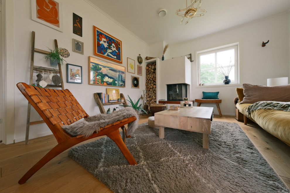 Exempel på ett mellanstort skandinaviskt allrum med öppen planlösning, med vita väggar, ljust trägolv, en öppen hörnspis, en spiselkrans i gips, en dold TV och brunt golv