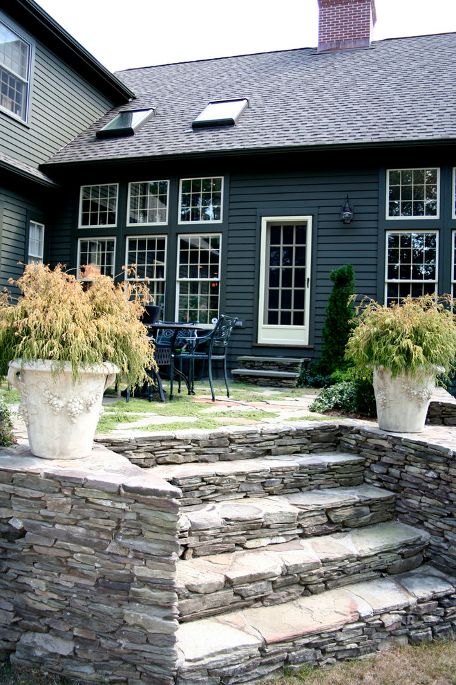 This is an example of a country backyard patio in New York with a container garden, natural stone pavers and no cover.