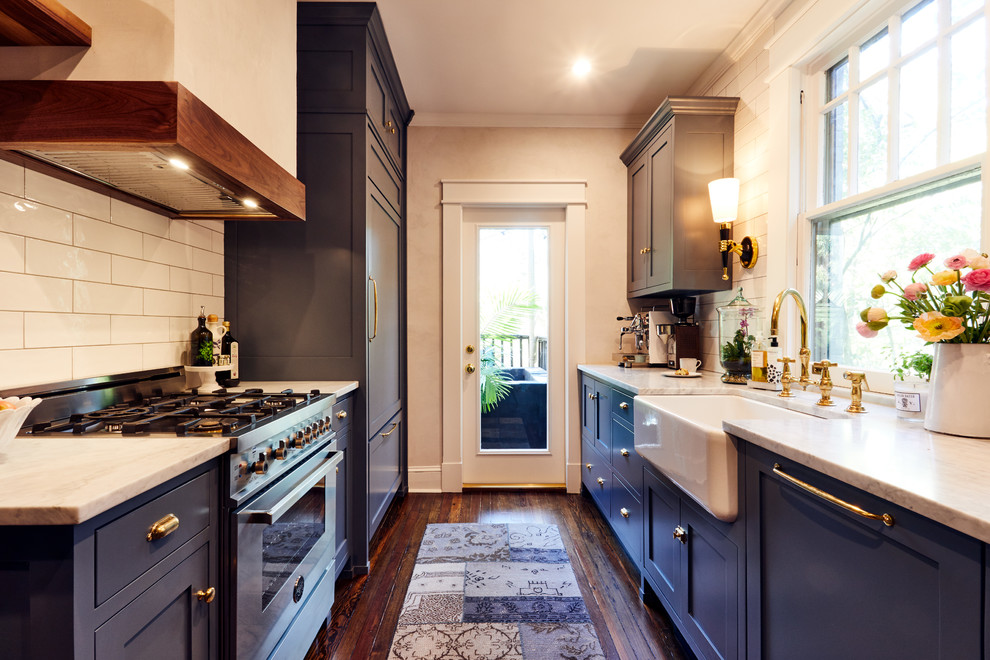 Small traditional galley separate kitchen in Atlanta with a farmhouse sink, shaker cabinets, blue cabinets, white splashback, subway tile splashback, stainless steel appliances, medium hardwood floors and no island.
