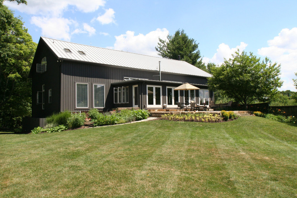 Photo of an expansive country three-storey grey exterior in Cleveland with wood siding.