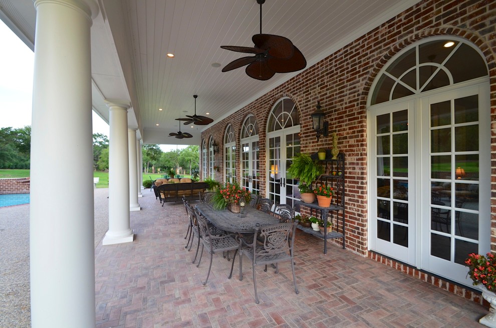 Expansive traditional backyard patio in Austin with brick pavers and a roof extension.