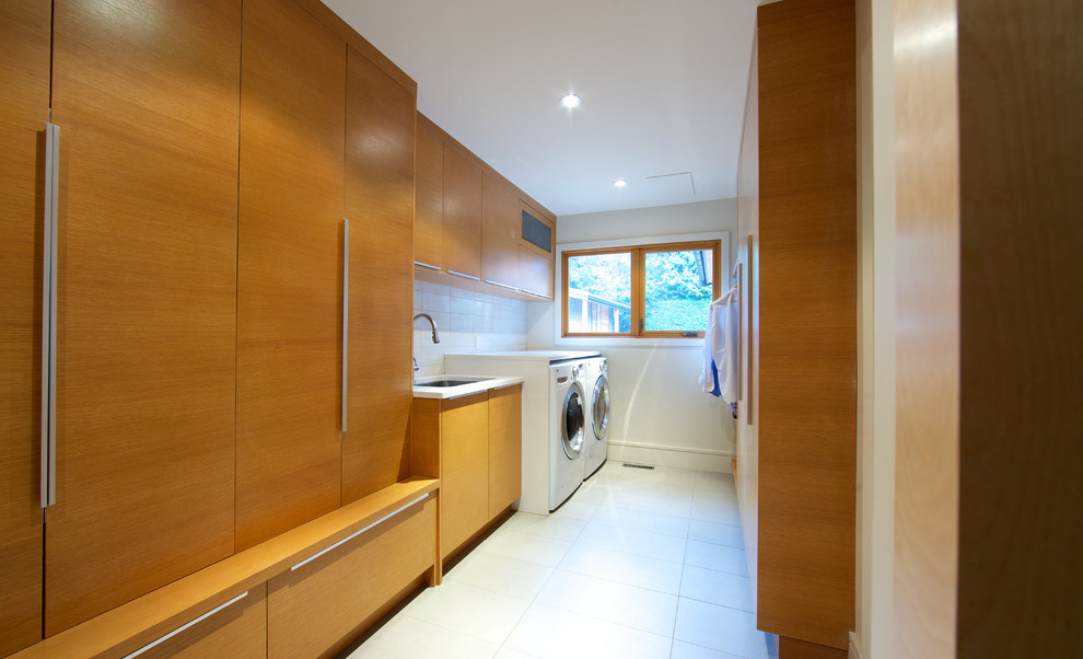 Large contemporary galley dedicated laundry room in Vancouver with an undermount sink, flat-panel cabinets, light wood cabinets, white walls, ceramic floors and a side-by-side washer and dryer.