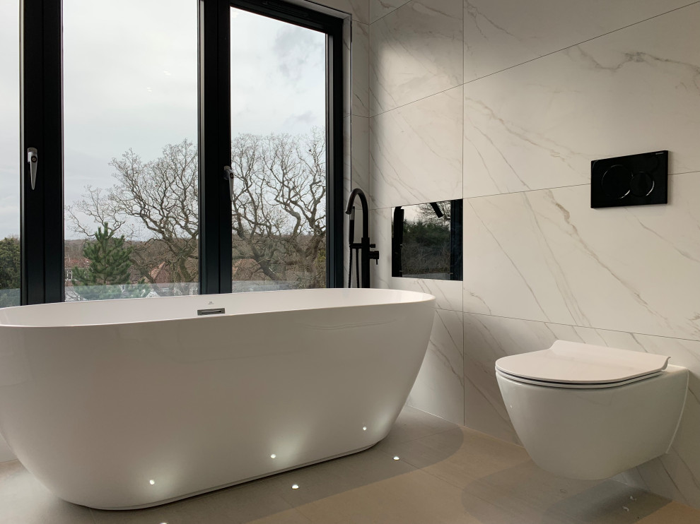 Large contemporary master wet room bathroom in London with flat-panel cabinets, white cabinets, a freestanding tub, a wall-mount toilet, white tile, porcelain tile, white walls, porcelain floors, a console sink, quartzite benchtops, grey floor, a hinged shower door, white benchtops, a niche, a single vanity and a floating vanity.
