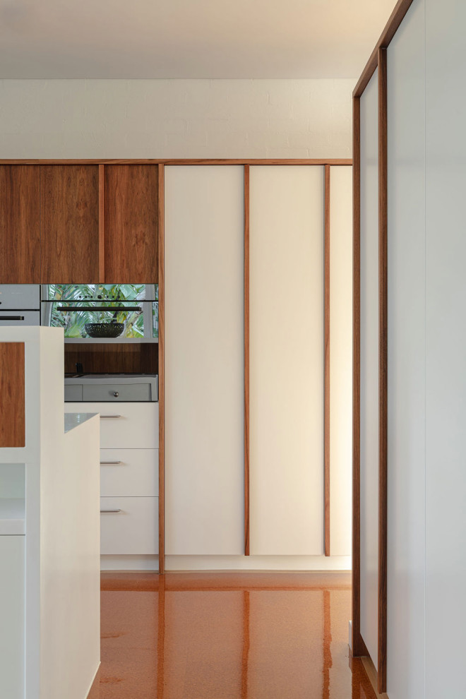 Design ideas for a mid-sized midcentury galley kitchen in Brisbane with medium wood cabinets, stone tile splashback and with island.