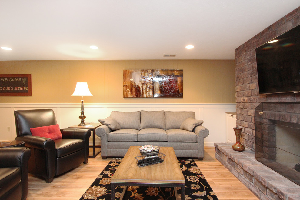 This is an example of a mid-sized traditional fully buried basement in Grand Rapids with beige walls, a standard fireplace and a brick fireplace surround.