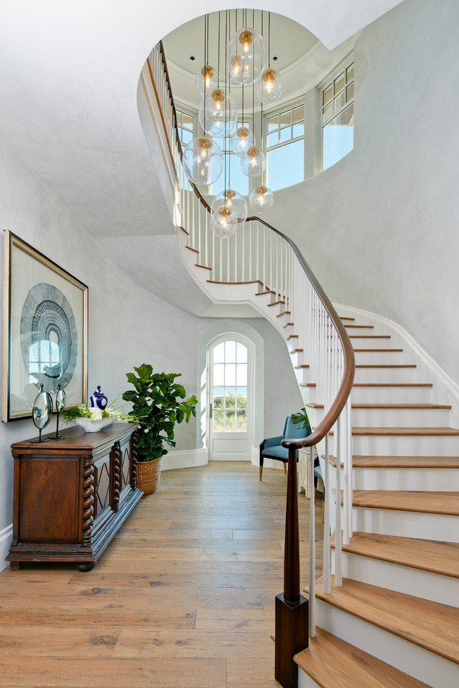 Mid-sized beach style wood curved staircase in Charleston with wood railing and painted wood risers.
