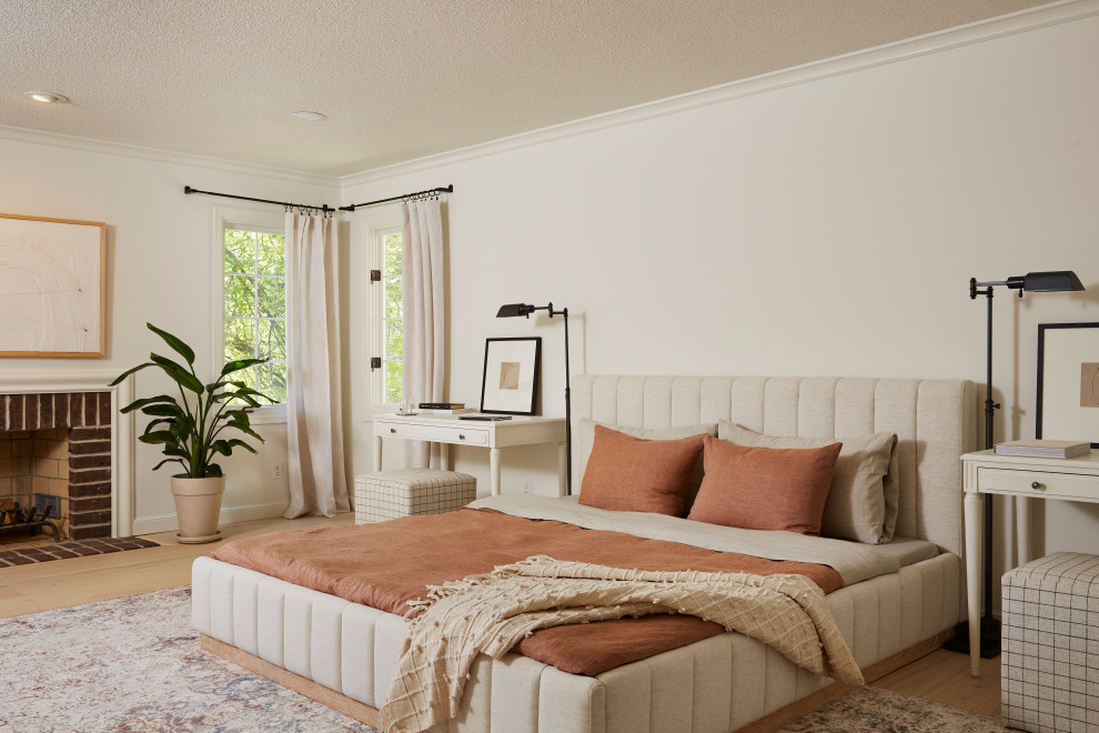 Idée de décoration pour une chambre parentale minimaliste de taille moyenne avec un mur blanc, parquet clair, une cheminée standard, un manteau de cheminée en brique et un sol beige.