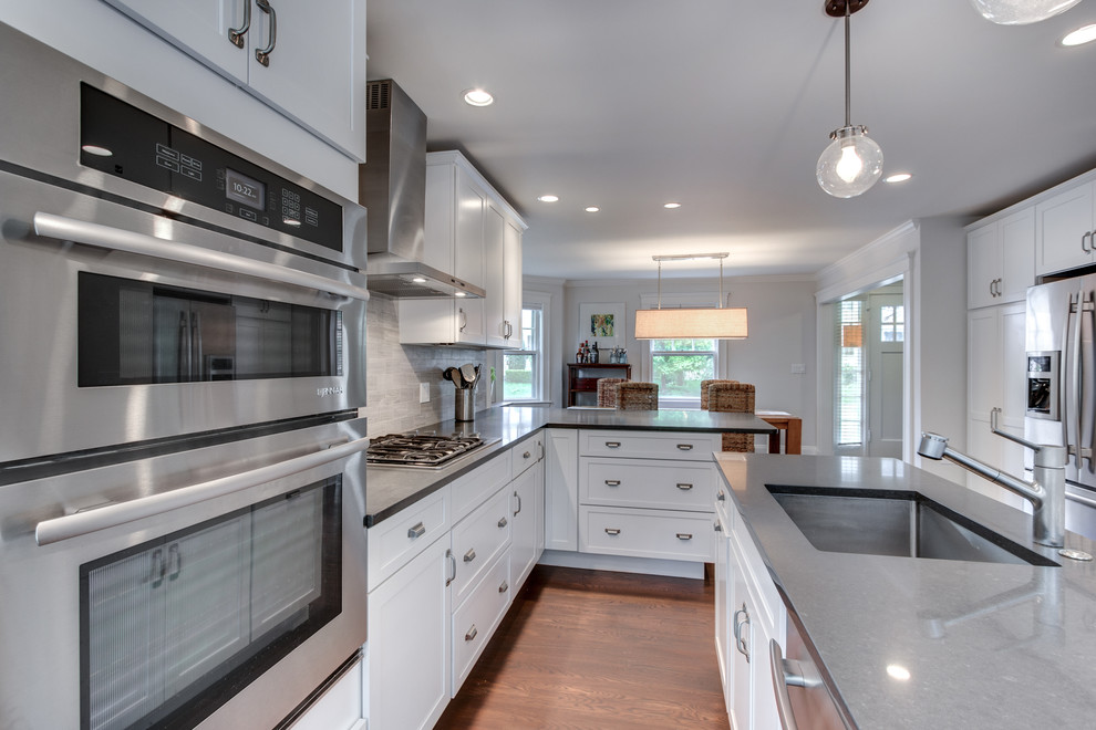 Mid-sized transitional l-shaped eat-in kitchen in Boston with an undermount sink, shaker cabinets, white cabinets, soapstone benchtops, grey splashback, stone tile splashback, stainless steel appliances, dark hardwood floors and with island.
