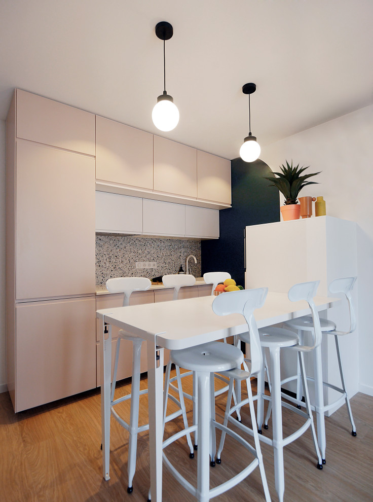Photo of a small modern single-wall open plan kitchen in Paris with a single-bowl sink, beaded inset cabinets, pink cabinets, laminate benchtops, multi-coloured splashback, ceramic splashback, white appliances, vinyl floors, beige floor and white benchtop.