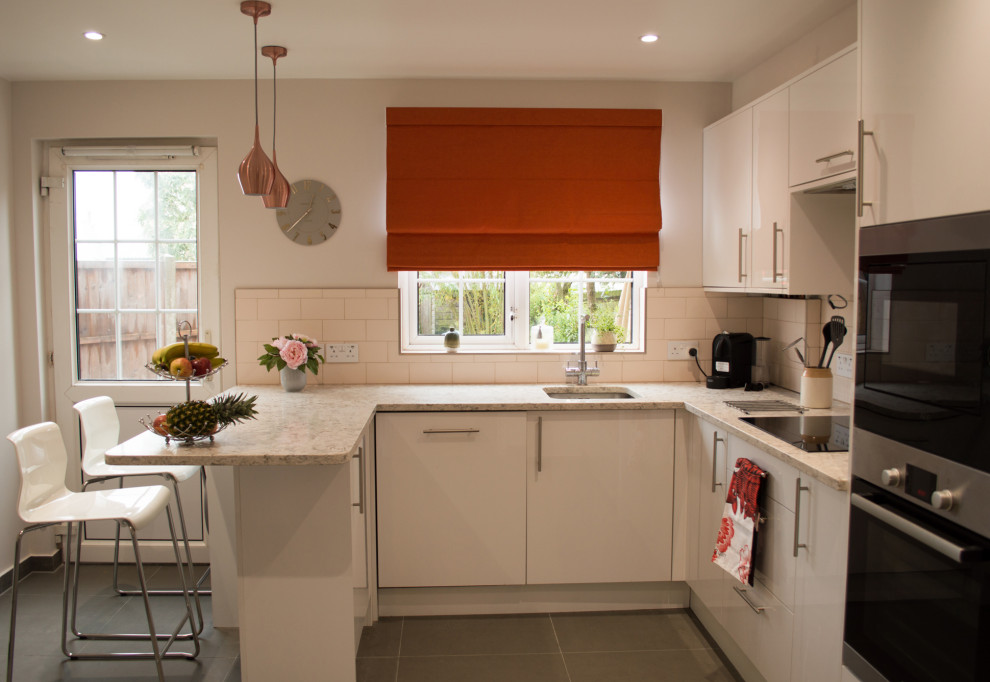 Mid-sized modern u-shaped separate kitchen in Hertfordshire with white cabinets, quartzite benchtops, pink splashback, ceramic splashback, with island, grey floor and beige benchtop.