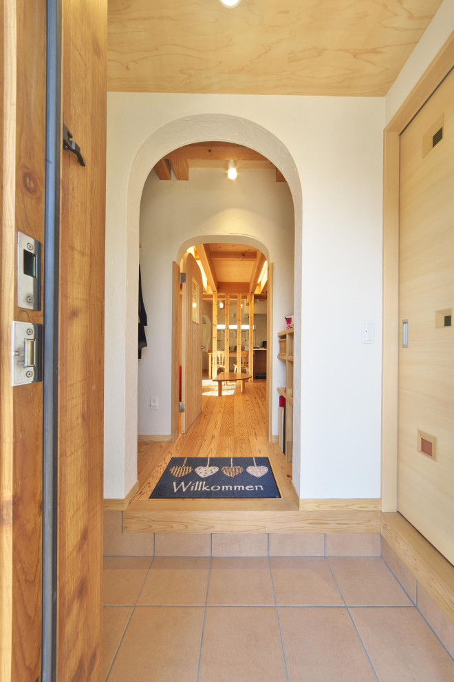 Esempio di un piccolo corridoio mediterraneo con pareti bianche, parquet chiaro, una porta singola, una porta in legno chiaro e soffitto in legno