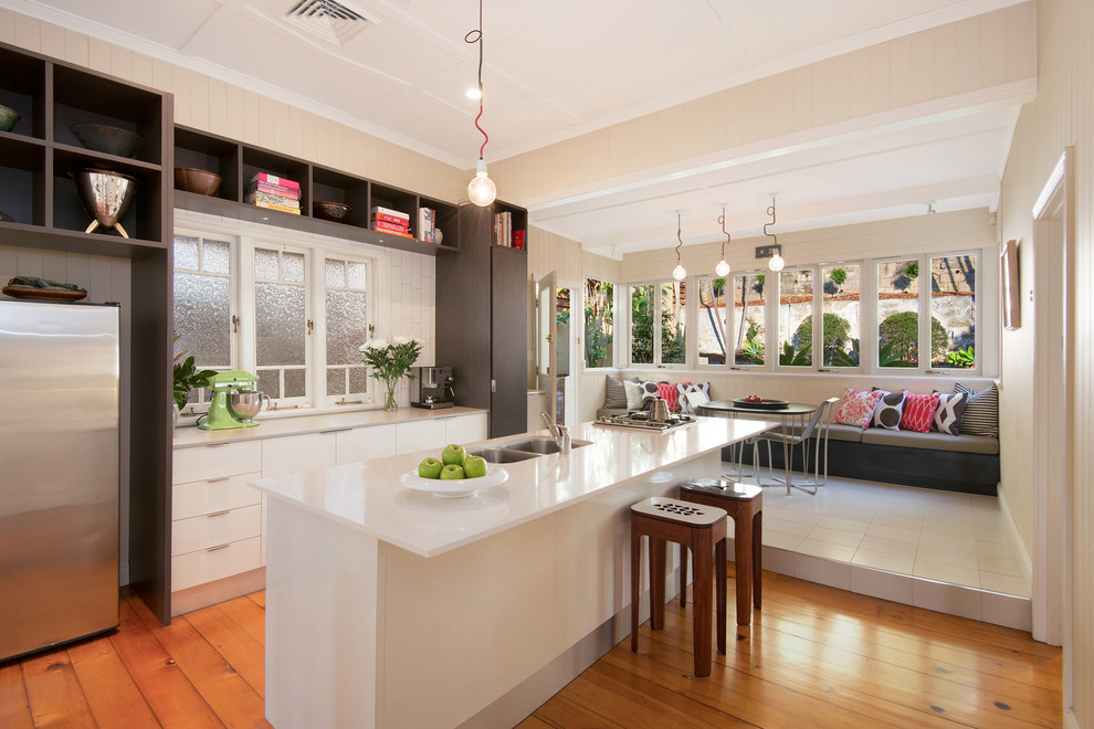 Contemporary galley eat-in kitchen in Brisbane with a double-bowl sink, flat-panel cabinets, white cabinets, stainless steel appliances, medium hardwood floors and with island.