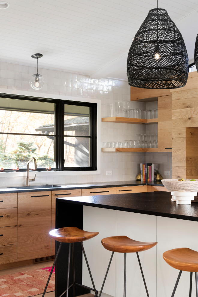 Inspiration for a large contemporary u-shaped medium tone wood floor and brown floor kitchen remodel in Minneapolis with flat-panel cabinets, light wood cabinets, granite countertops, white backsplash, an island, an undermount sink and black countertops