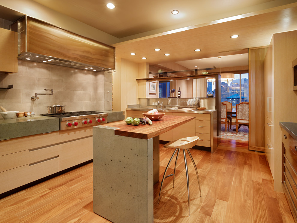 Photo of a mid-sized modern u-shaped eat-in kitchen in San Francisco with a farmhouse sink, flat-panel cabinets, light wood cabinets, concrete benchtops, grey splashback, ceramic splashback, stainless steel appliances, medium hardwood floors and with island.