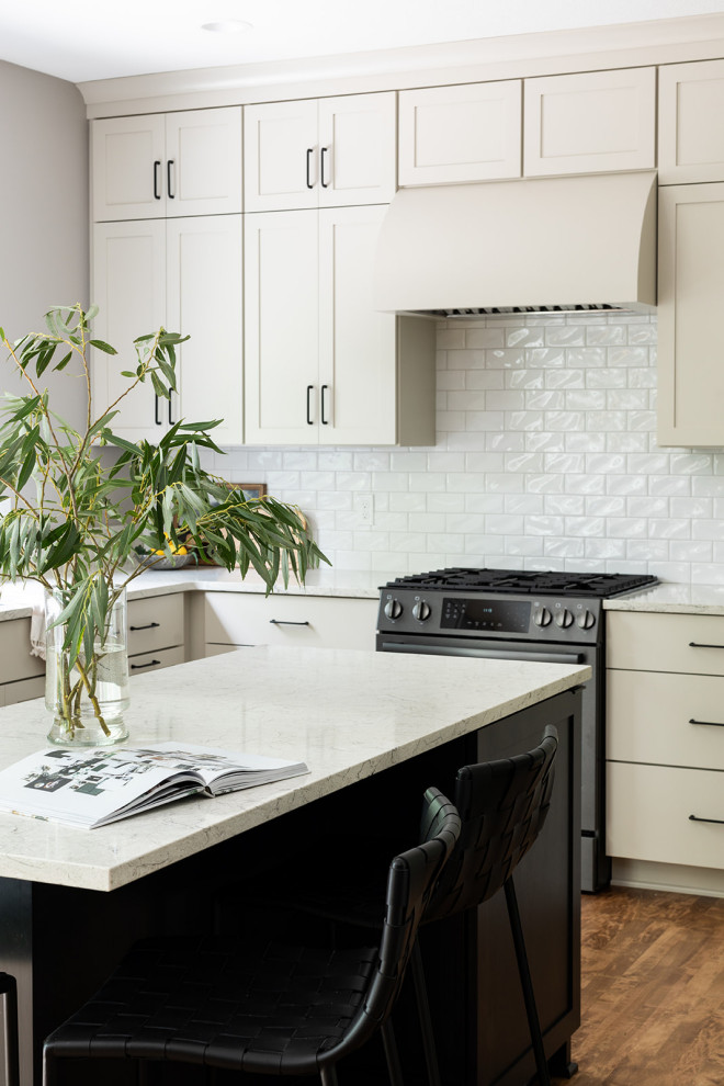 Eat-in kitchen - mid-sized transitional u-shaped medium tone wood floor and brown floor eat-in kitchen idea with an undermount sink, shaker cabinets, white cabinets, quartz countertops, white backsplash, subway tile backsplash, black appliances, an island and white countertops