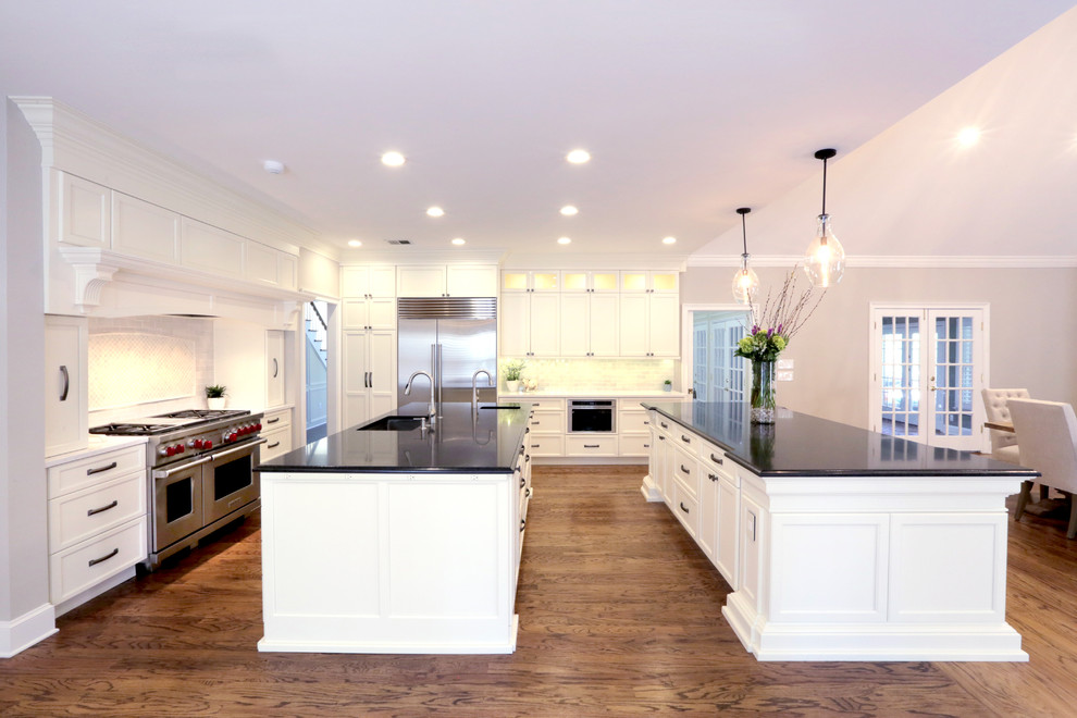 Large elegant u-shaped light wood floor eat-in kitchen photo in Jacksonville with white cabinets and two islands