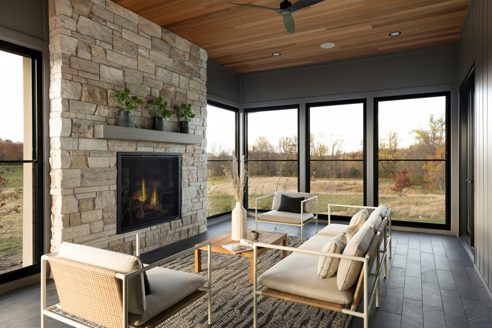 Photo of a medium sized country back veranda in Minneapolis with a fireplace, tiled flooring and a roof extension.