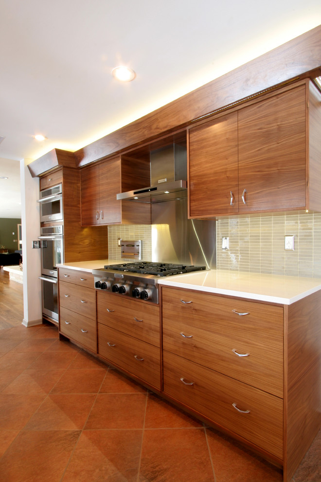 This is an example of a large midcentury galley eat-in kitchen in Milwaukee with flat-panel cabinets, medium wood cabinets, quartz benchtops, glass tile splashback, stainless steel appliances, ceramic floors and no island.