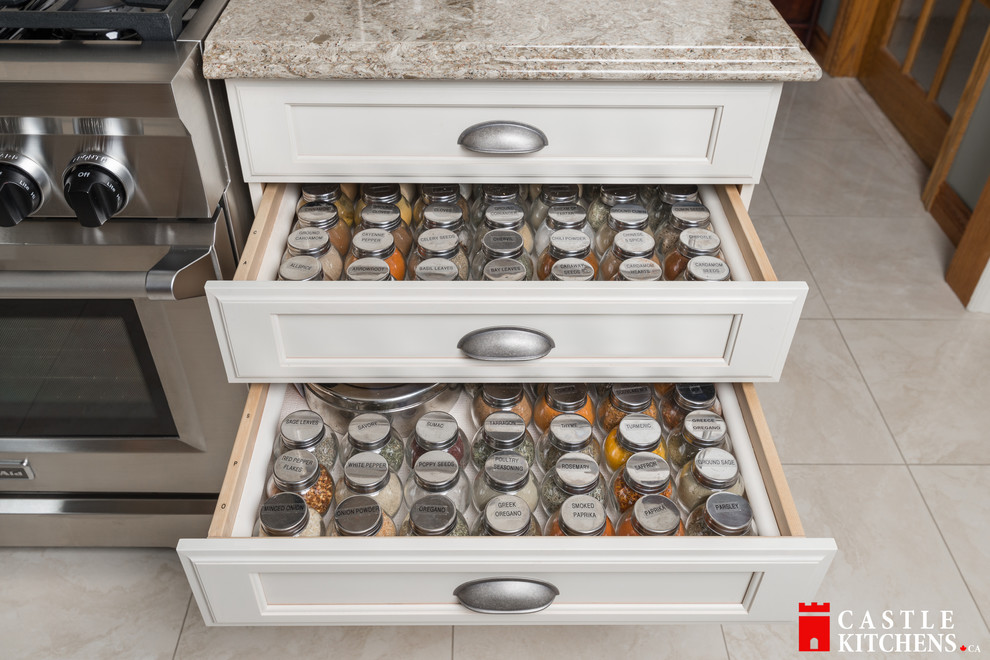 Enclosed kitchen - mid-sized transitional galley porcelain tile enclosed kitchen idea in Toronto with an undermount sink, shaker cabinets, beige cabinets, quartzite countertops, beige backsplash, stainless steel appliances and an island