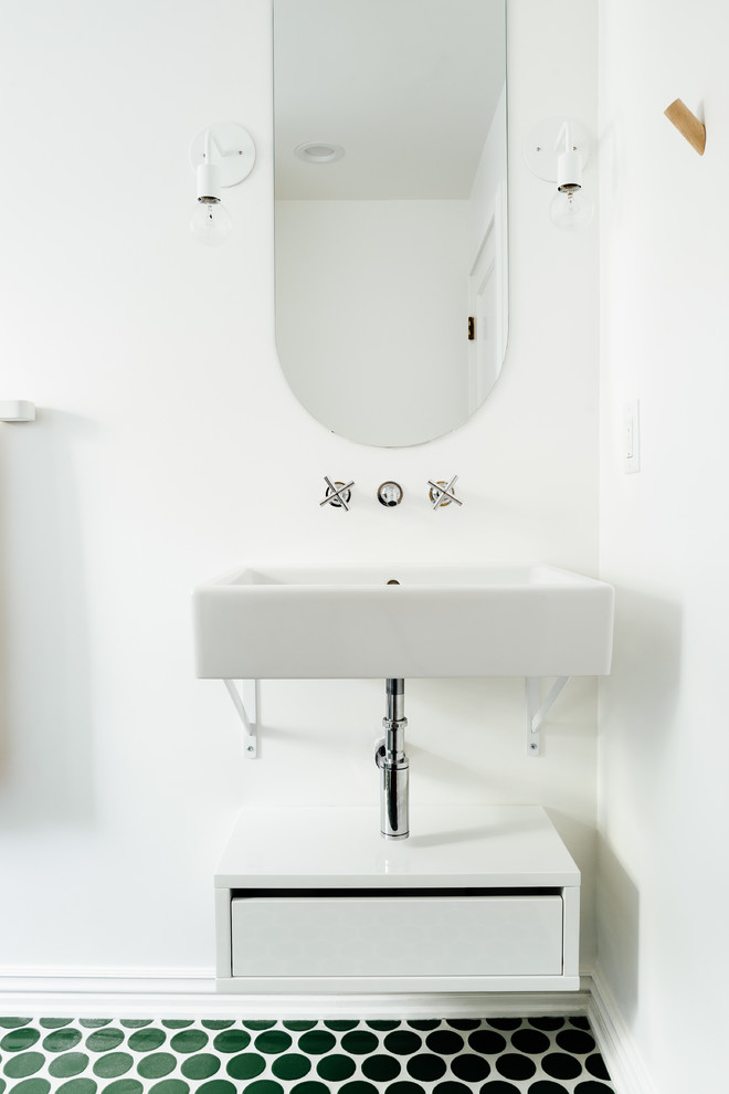 This is an example of a small scandinavian powder room in Salt Lake City with white walls, porcelain floors, a wall-mount sink, green floor, flat-panel cabinets and white cabinets.